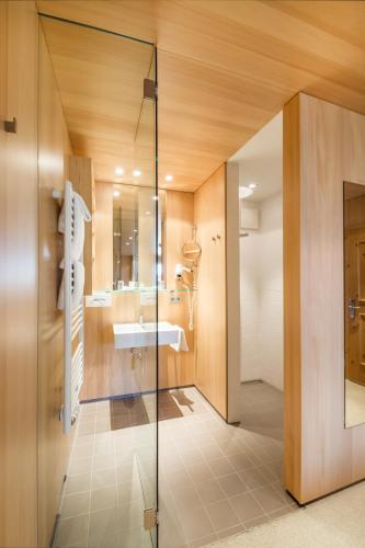 a bathroom with a glass shower and a sink at Superior Hotel Alpenhof in Flachau