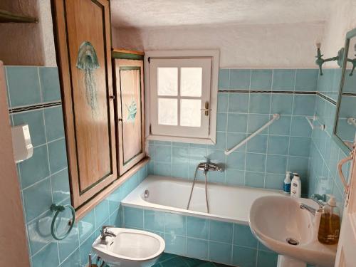 a blue tiled bathroom with a tub and a sink at Ventus Auster in Olbia