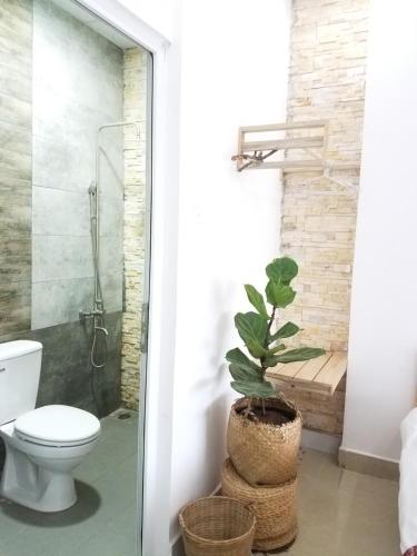a bathroom with a toilet and a shower and a plant at Làng Kò Hơ hotel in Da Lat