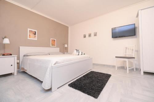 een witte slaapkamer met een bed en een flatscreen-tv bij Canova apartment in Noto