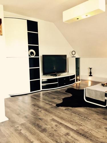 a living room with a television and a wooden floor at Ferienwohnung H&H Happy Holiday in Velden am Wörthersee