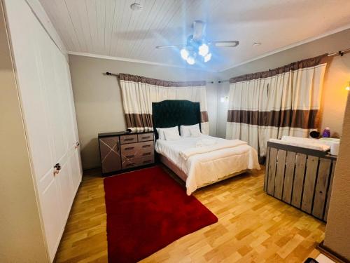 a bedroom with a bed and a red rug at Khans Residence in Gqeberha