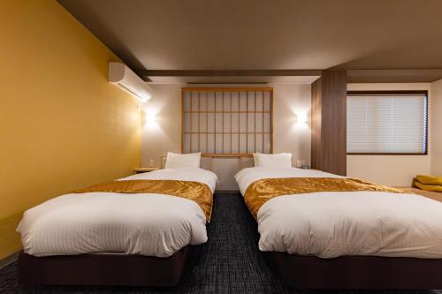 two beds in a hotel room with at MADOKA Kyoto station west in Kyoto