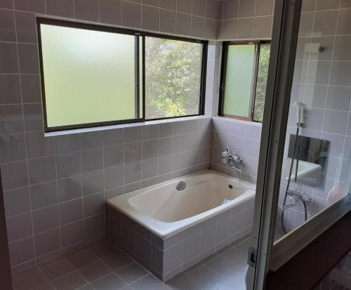 a bath tub in a bathroom with two windows at Cozy Koharuka in Shima