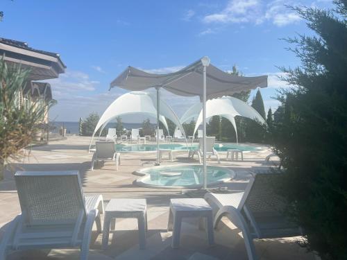 a patio with chairs and an umbrella and a pool at Dacha Del Mar in Yasnogorodka