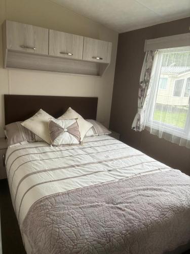 a bedroom with a large bed with pillows and a window at Beach Retreats, Romney Sands, Parkdean Resorts in Greatstone