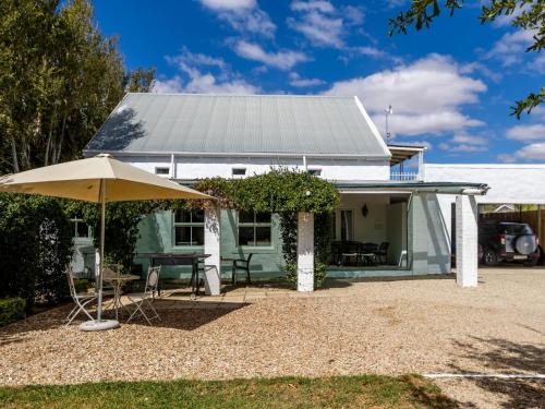 a green house with a table and an umbrella at Julie's Cottage in Riebeek-Kasteel