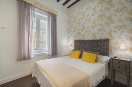 a bedroom with a bed with yellow pillows and a window at Palacete de La Alameda - Adults Only- in Cádiz