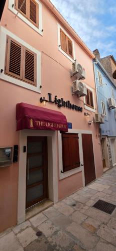 a pink building with a red awning on it at Lighthouse Zadar Center Apartments in Zadar