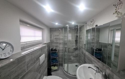 a bathroom with a shower and a sink and a clock at Casa Mia 36 am See in Joachimsthal