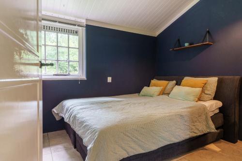 a bedroom with a bed with blue walls and a window at Bungalow de Mees in Schoonloo