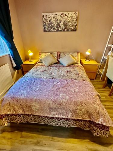 a bed in a room with two lamps on tables at NKN cosy maisonette close to Dartford train station, free parking, food, shopping in Kent