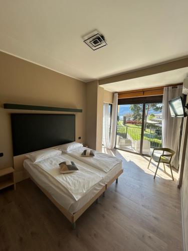 a bedroom with a large bed and a large window at Hotel Camping Europa in Domaso