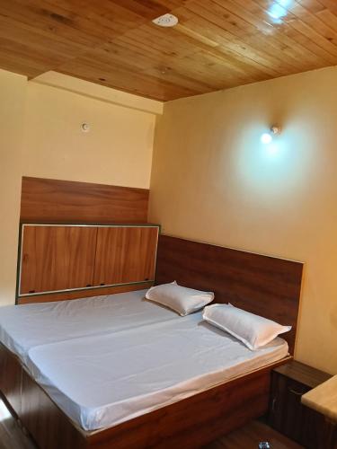 a bed in a room with a wooden ceiling at Divine homestay in Kukri Ser