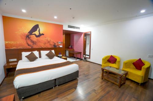 a bedroom with a large bed and a yellow chair at The Royal Comfort in Bangalore