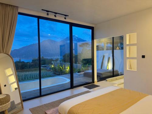 a bedroom with a large window with a view of a tub at Aluna Villa Kintamani - Private villa & Hot spring pool in Kubupenlokan