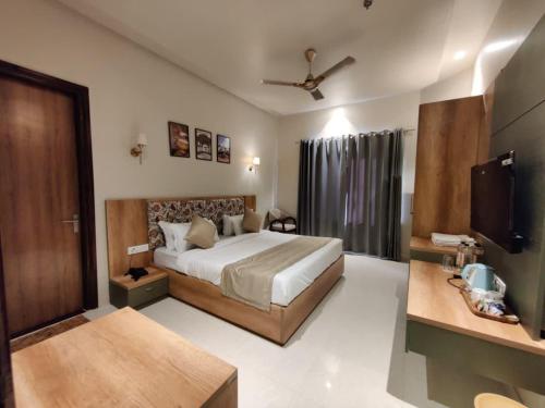 a hotel room with a bed and a television at Infinity Hotel & Resort, Chikani , Alwar in Alwar