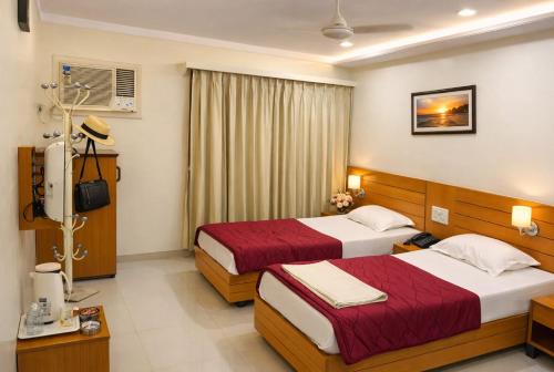 a hotel room with two beds and a television at Hotel Sarita - Near Surat Railway Station in Surat