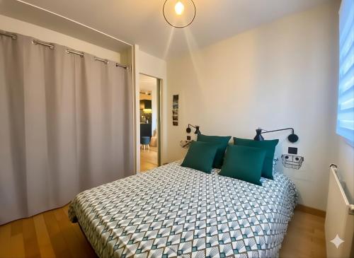 a bedroom with a large bed with green pillows at La Pause de Mérimée - Jardin - Parking in Vannes