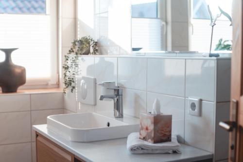a white bathroom with a sink and a mirror at Ferienhaus FachWerkPerle am Alfsee in Rieste