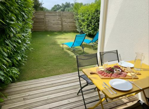 a yellow table with a plate of food on a patio at La Pause de Mérimée - Jardin - Parking in Vannes