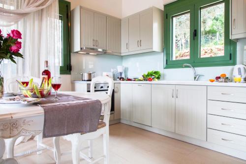 a kitchen with white cabinets and a table with glasses of wine at Ktima Aniforeli Luxury Villas in Sivota