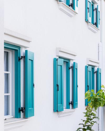 a row of blue shuttered windows on a white building at Casa Calypso in Tselendáta