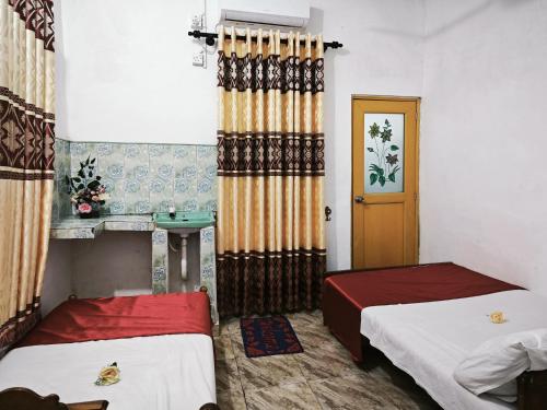 a small room with two beds and a door at JP Rest House in Trincomalee