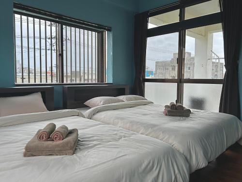 two beds in a room with two large windows at 一棟貸しハウスまれち in Kumejima