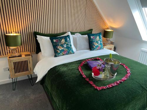 a bedroom with a green bed with a heart made out of flowers at THE HIDEAWAY - LUXURY SELF CATERING COASTAL APARTMENT with PRIVATE ENTRANCE & KEY BOX ENTRY JUST A FEW MINUTES WALK TO THE BEACH, SOLENT WAY WALK, SHOPS and many EATERIES & BARS - FREE OFF ROAD PARKING,FULL KITCHEN, LOUNGE,BEDROOM , BATHROOM & WI-FI in Lymington
