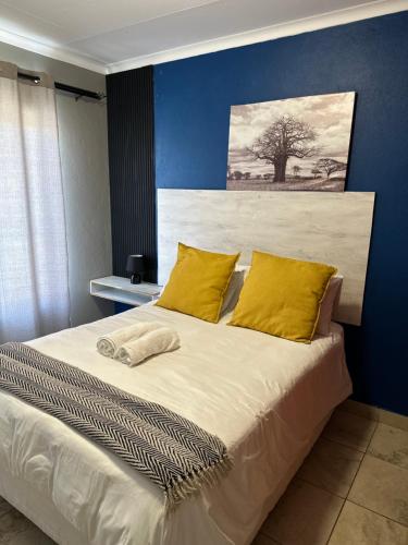 a bedroom with a large bed with yellow pillows at Waterfall Deluxe in Rustenburg