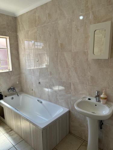 a bathroom with a tub and a sink at Waterfall Deluxe in Rustenburg