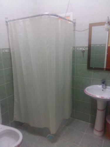 a bathroom with a shower curtain and a sink at Five Continents Hotel in Sur