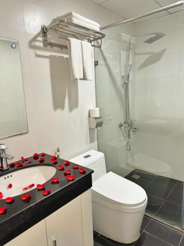 a bathroom with a toilet and a sink with red rose pedals at Sunrise Villa Hanoi in Hanoi
