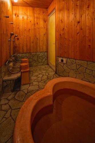 a bathroom with a large tub in a wooden room at Twin Dome Ryugu in Hokuto
