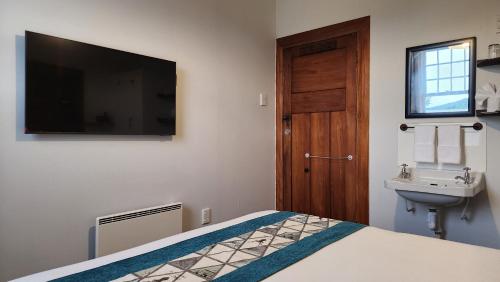 a bedroom with a bed and a sink and a television at Alexandra Hotel in Pirongia