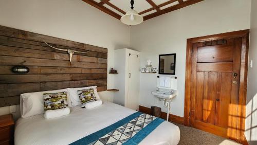 a bedroom with a bed with a wooden headboard and a sink at Alexandra Hotel in Pirongia