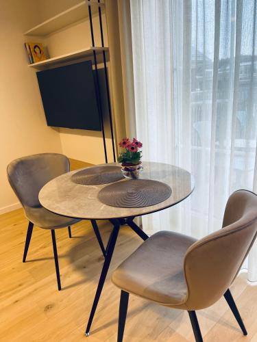 ein Tisch mit zwei Stühlen und einer Blumenvase darauf in der Unterkunft Marè studio in Neringa