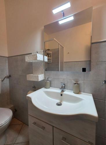 a bathroom with a sink and a mirror and a toilet at Il Melangolo in SantʼAntìoco