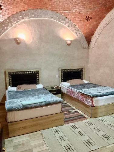 two beds in a room with a brick wall at King Siwa in Siwa