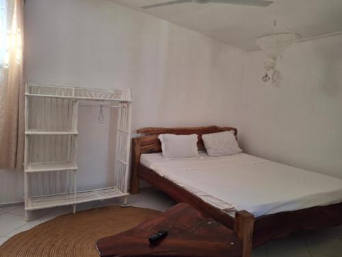 a small bedroom with a bed and a shelf at Susans cottages diani beach in Ukunda