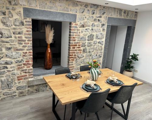 a dining room with a wooden table and a brick wall at Appartement chez pépite in Namur