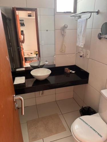 a bathroom with a sink and a mirror and a toilet at Iloa Residence V13 Beach - localização privilegiada in Barra de São Miguel