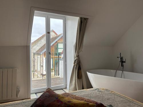 a bathroom with a tub and a large window at Relais du Chat Prosper in Lescherolles