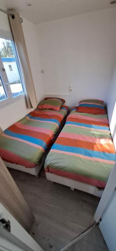 two beds sitting next to each other in a room at Mobil home proche Fréjus - Camping 4 étoiles in Puget-sur-Argens