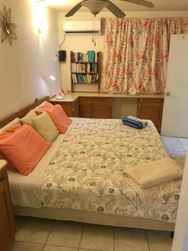 a bedroom with a bed with orange pillows on it at Golden Gem Cosy Apartment with pool & garden view in Saint James