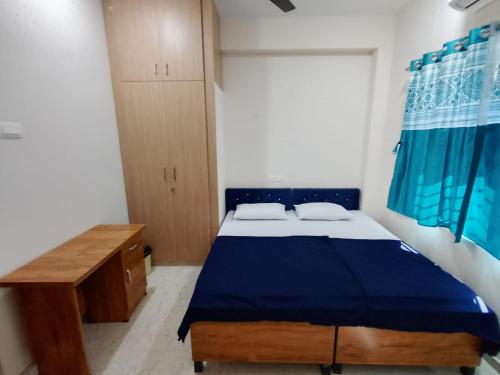 a bedroom with a blue bed and a wooden desk at RV Comforts in Siruvāchchūr