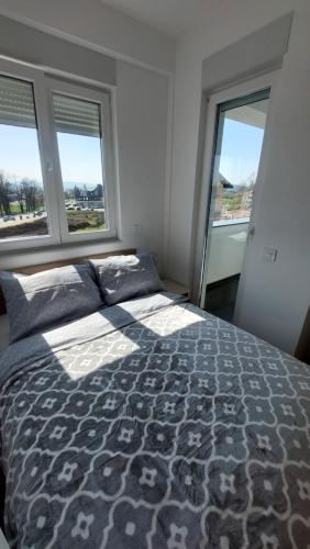 a bedroom with a large bed and two windows at Apartman Stan Laktasi in Laktaši
