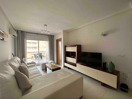 a living room with a white couch and a television at Magic World Vistamar lll in El Borseral