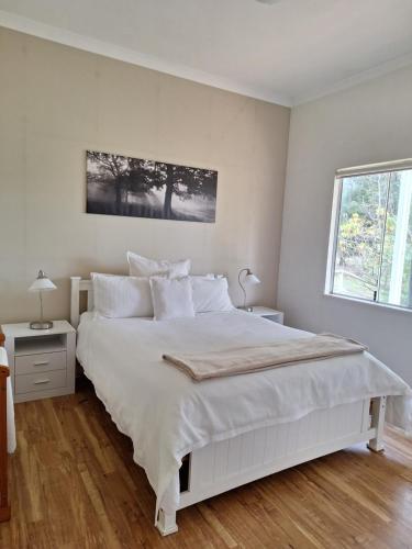 a white bedroom with a white bed and a window at Abbivale Farm Cottage in Harewood